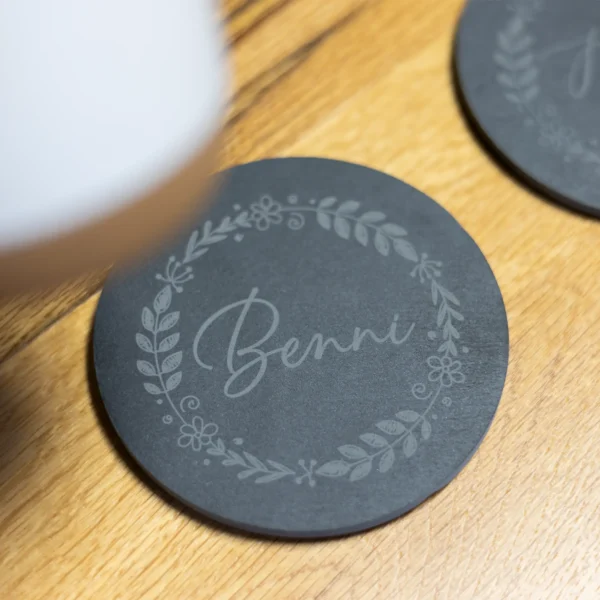Personalisierte Schieferuntersetzer mit Gravur und floralem Design - Tasse wird von Untersetzer gehoben